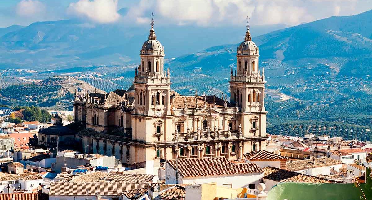 Iglesia colonial con torres, rodeada de montañas y un paisaje urbano en jaén