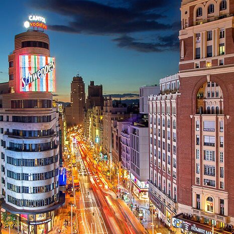 Vista nocturna de una ciudad con edificios iluminados y tráfico en las calles.