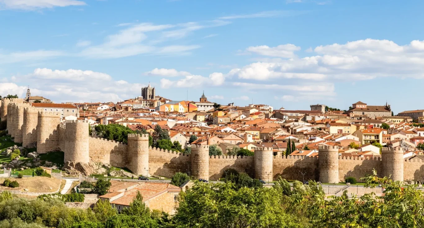 Vista panorámica de una ciudad amurallada con casas y colinas al fondo EN ÁVILA