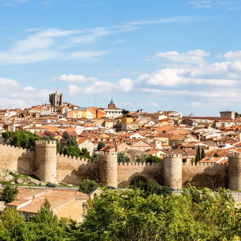 Panorámica de Ávila con murallas y edificios históricos bajo un cielo despejado.