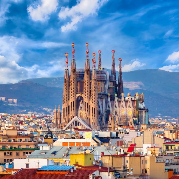 La Sagrada Familia se alza sobre el paisaje urbano de Barcelona, con un cielo azul de fondo.