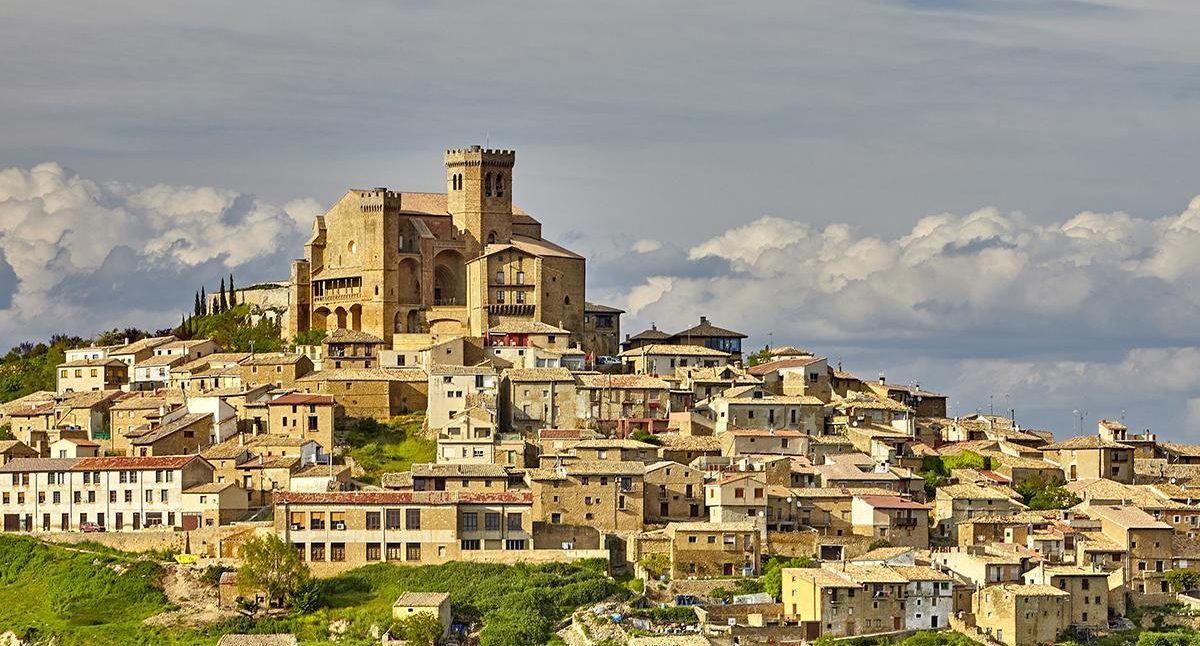 Castillo en lo alto de una colina rodeado de casas y nubes en el cielo de NAVARRA