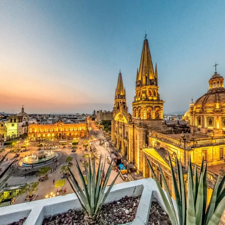 Vista panorámica de la ciudad con catedrales iluminadas al atardecer.