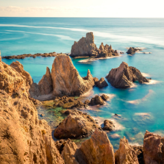 Formaciones rocosas en el agua con un cielo claro y un mar en calma.