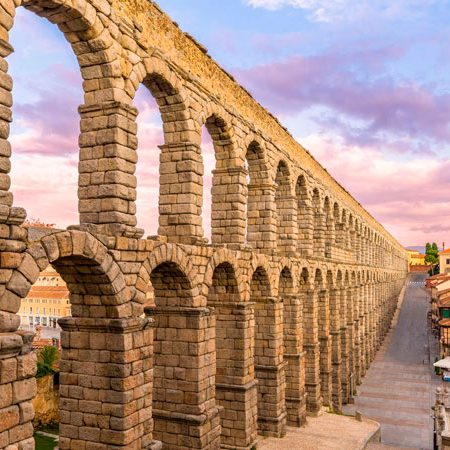 Acueducto romano de Segovia al atardecer con arcos de piedra.