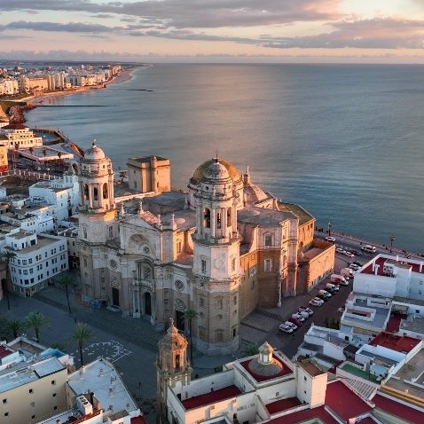 Catedral de Cádiz vista desde arriba, junto al mar y la ciudad al fondo.