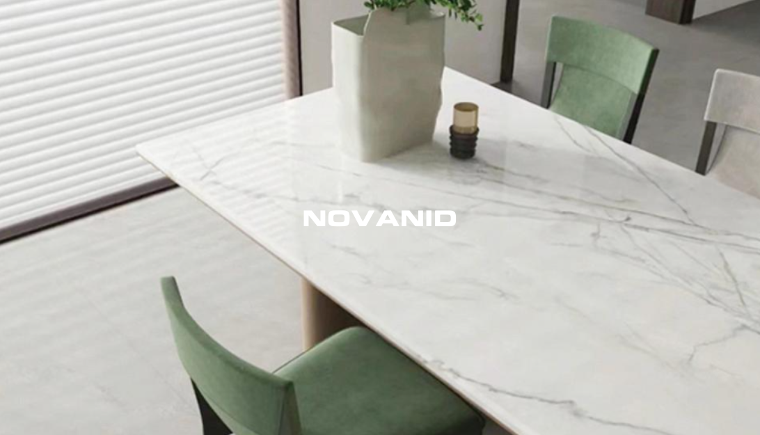 Mesa con PLACA DECORATIVA mármol blanco STATUARIO NOVANID y sillas verdes, decorada con una planta y una vela.