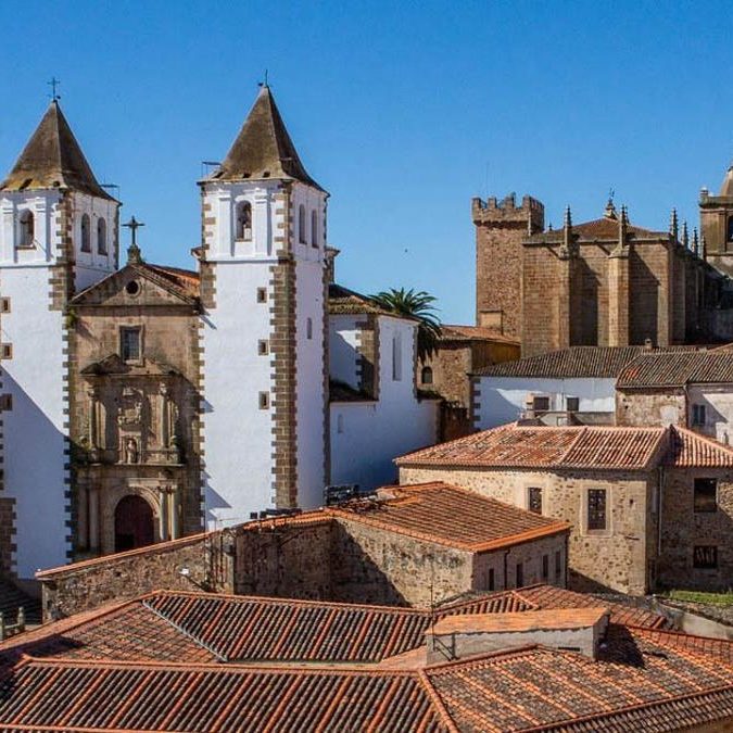 Vista de un pueblo con iglesias de torres y casas de techos de tejas en Caceres