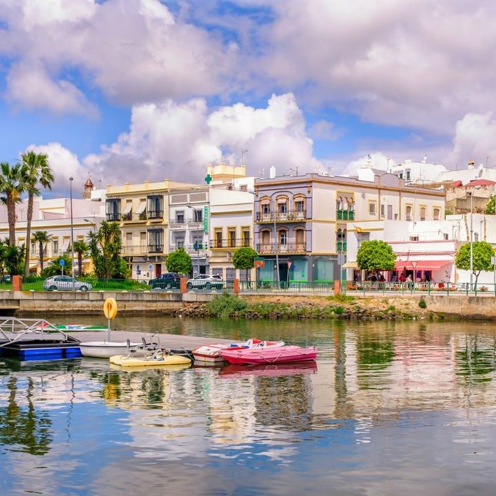 Vista de un puerto con casas coloridas y botes reflejados en el agua.