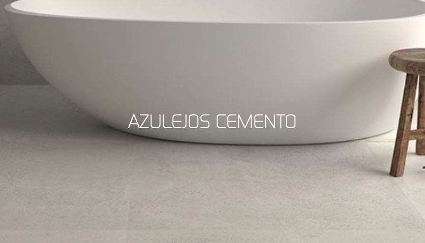 Bañera blanca ovalada sobre suelo de azulejos de cemento, con un taburete de madera al lado.