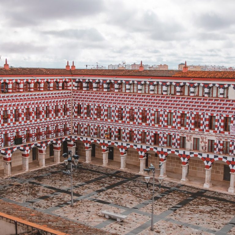 Plaza de España en Salamanca, con fachadas decoradas y nubes en el cielo.