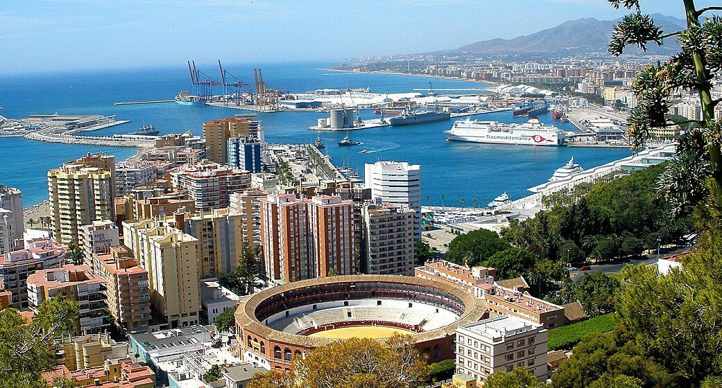 Vista panorámica del puerto y la ciudad, con una plaza de toros en primer plano de málaga