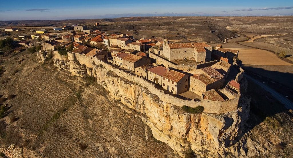 Pueblo histórico situado en un acantilado con casas y campos de cultivo alrededor en Soria
