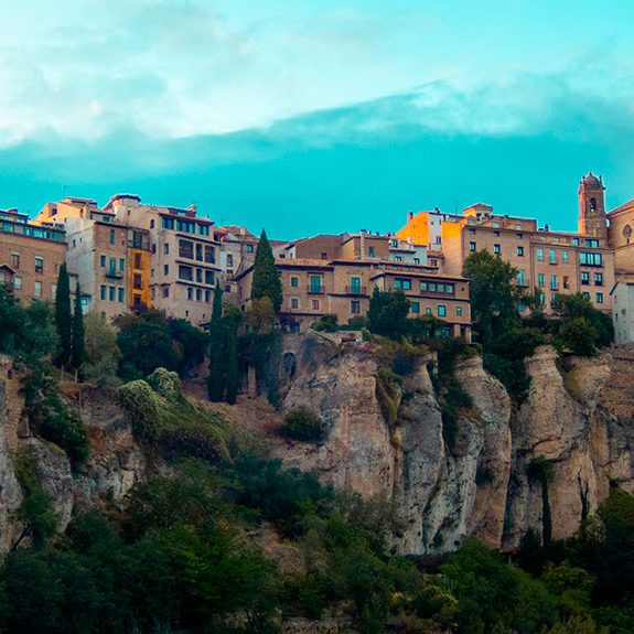 Panorama de un pueblo construido sobre acantilados, rodeado de vegetación y montañas.