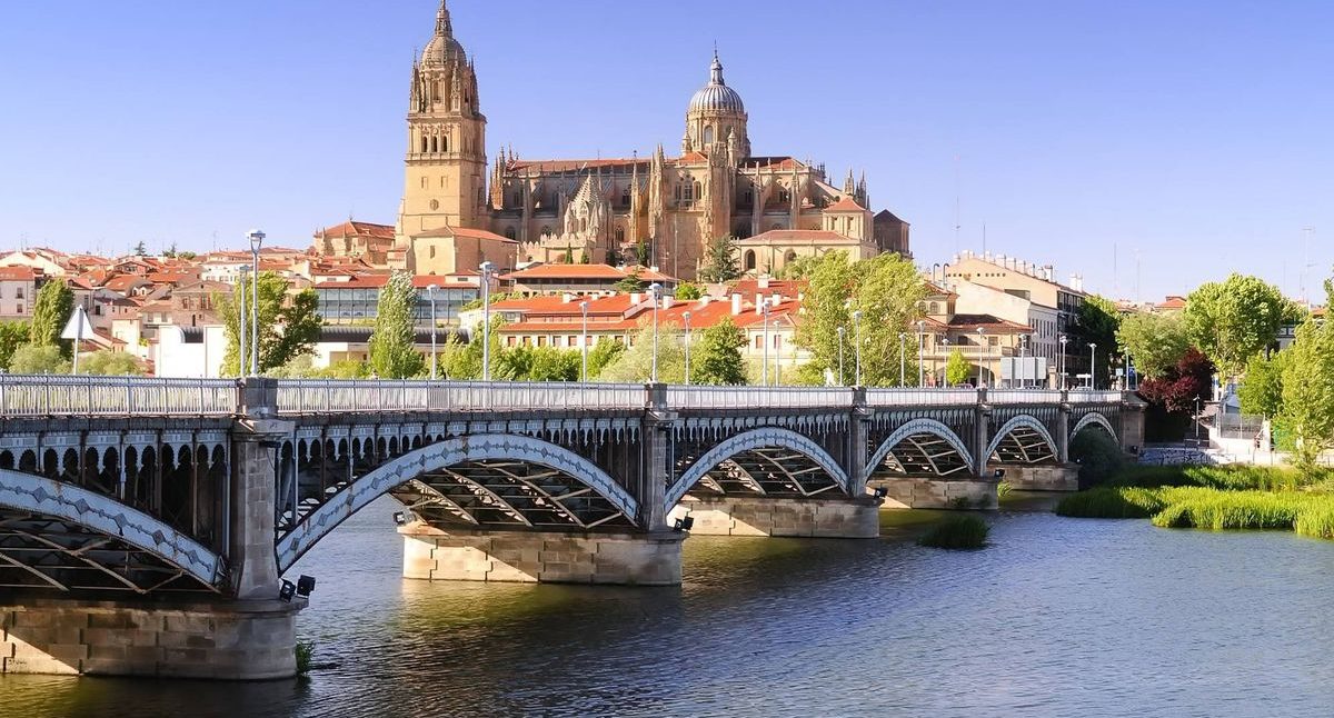 Puente sobre el río con vista a la catedral y edificios de Salamanca al fondo.
